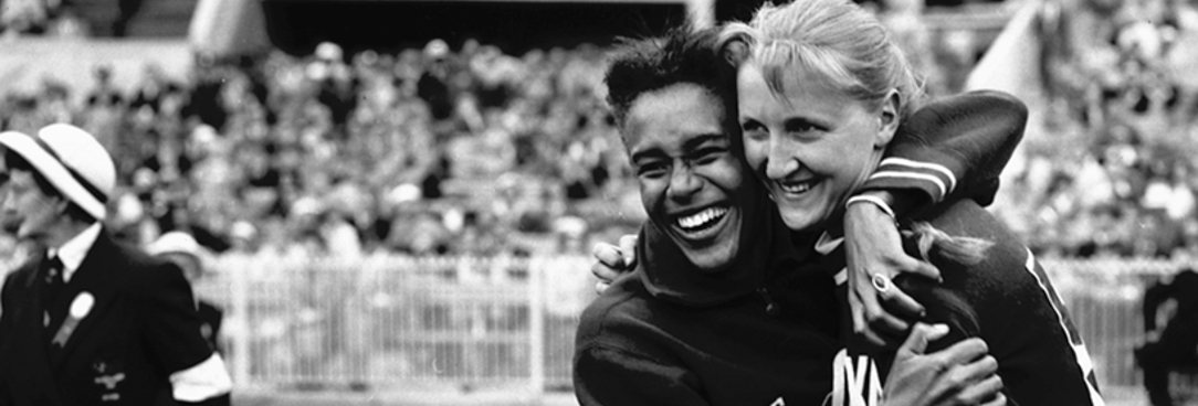 A black and white photo of two women hugging at the 1956 Olympic games