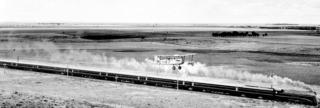 Black and white photo of a plane and a train