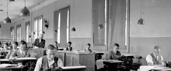 Black and white photo of people sitting at desks
