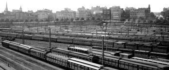 Black and white photo of trains in city rail yard