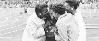 black and white photo of women on a race track hugging after a winning race